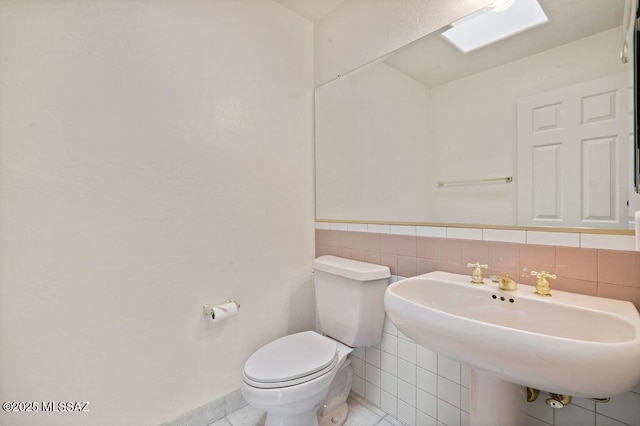 11126 N Guava Dr, Oro Valley, AZ 85737 - bathroom with toilet, a sink, tile patterned floors, tile walls, and a skylight
