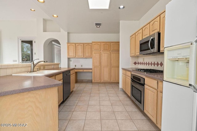 11126 N Guava Dr, Oro Valley, AZ 85737 - kitchen with stainless steel appliances, light brown cabinetry, a sink, arched walkways, and decorative backsplash