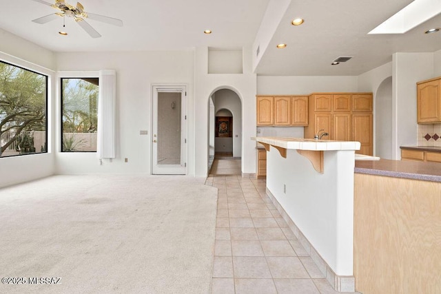 11126 N Guava Dr, Oro Valley, AZ 85737 - kitchen with arched walkways, recessed lighting, light tile patterned floors, a ceiling fan, and light brown cabinets