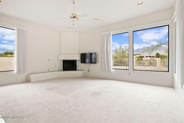 11126 N Guava Dr, Oro Valley, AZ 85737 - unfurnished living room featuring carpet flooring, a fireplace with raised hearth, healthy amount of natural light, recessed lighting, and ceiling fan