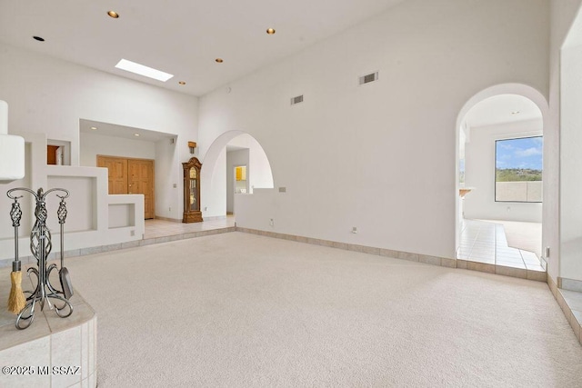 11126 N Guava Dr, Oro Valley, AZ 85737 - unfurnished living room featuring a towering ceiling, arched walkways, recessed lighting, and baseboards