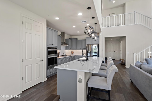 7809 S Land Grant Dr, Tucson, AZ 85747 - kitchen featuring gray cabinetry, a sink, appliances with stainless steel finishes, wall chimney range hood, and dark wood-style floors