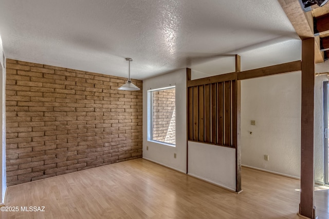 2777 N Treat Ave, Tucson, AZ 85716 - unfurnished dining area with a textured ceiling, brick wall, wood finished floors, and baseboards