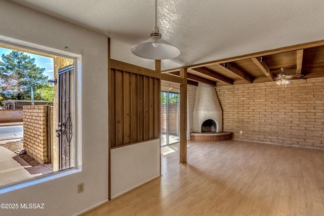 2777 N Treat Ave, Tucson, AZ 85716 - unfurnished living room with brick wall, wood finished floors, a ceiling fan, and a textured ceiling