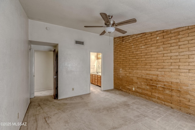 2777 N Treat Ave, Tucson, AZ 85716 - unfurnished bedroom with brick wall, light colored carpet, baseboards, ceiling fan, and ensuite bath