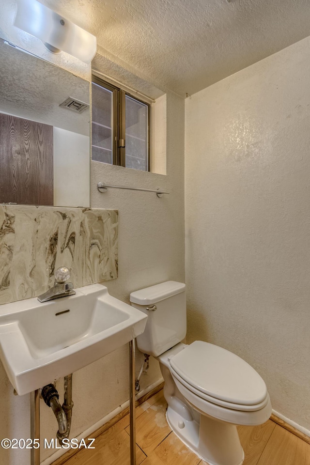 2777 N Treat Ave, Tucson, AZ 85716 - half bath featuring wood finished floors, baseboards, toilet, and a textured ceiling