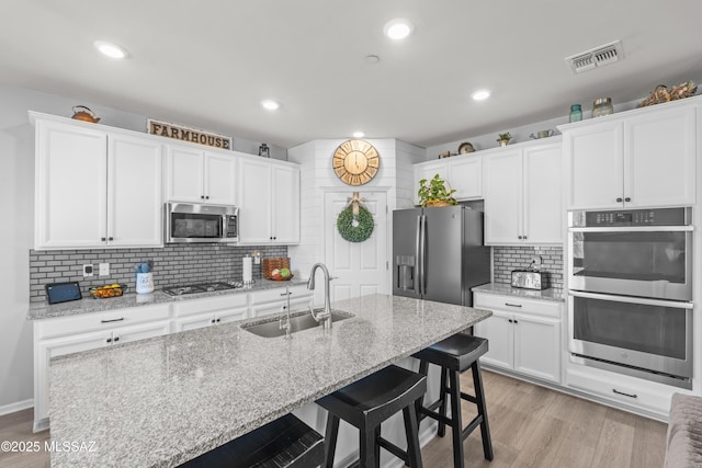 17303 S Nicholas Falls Dr, Vail, AZ 85641 - kitchen with a sink, appliances with stainless steel finishes, decorative backsplash, white cabinetry, and a breakfast bar area