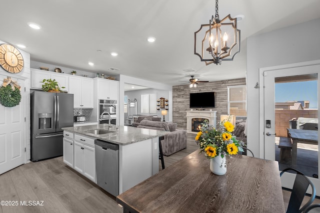 17303 S Nicholas Falls Dr, Vail, AZ 85641 - kitchen with appliances with stainless steel finishes, a ceiling fan, a large fireplace, light wood finished floors, and a sink