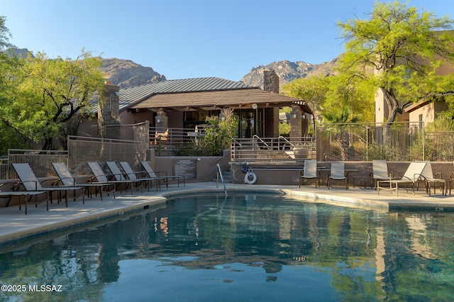 community pool with a mountain view, a patio area, and fence