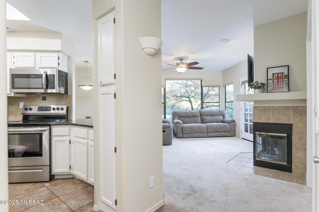 kitchen with appliances with stainless steel finishes, a ceiling fan, white cabinets, and light colored carpet
