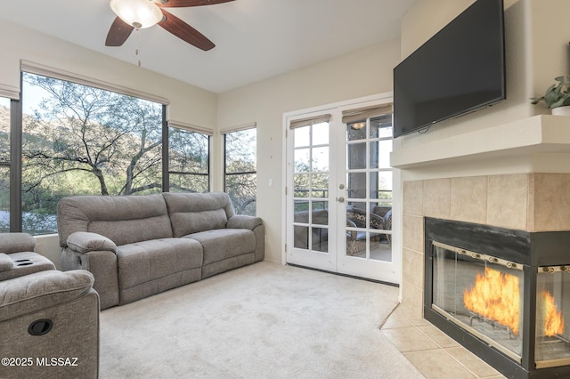 living room with ceiling fan, healthy amount of natural light, a tiled fireplace, and carpet