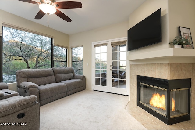 living area featuring french doors, a tiled fireplace, plenty of natural light, and ceiling fan