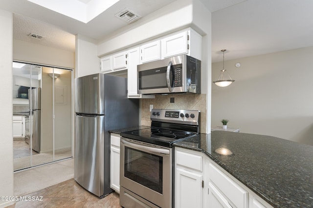 kitchen with appliances with stainless steel finishes, white cabinetry, backsplash, dark stone counters, and decorative light fixtures