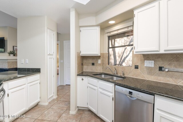 kitchen featuring stainless steel dishwasher, a sink, white cabinets, light tile patterned floors, and dark stone counters