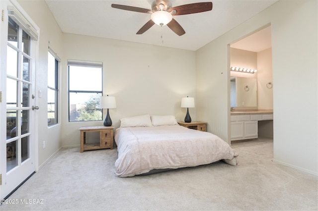 bedroom featuring light carpet, baseboards, ensuite bathroom, and a ceiling fan