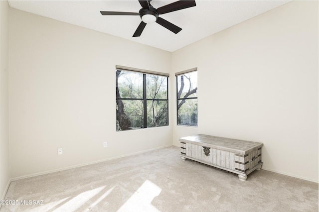 spare room featuring light carpet, baseboards, and a ceiling fan