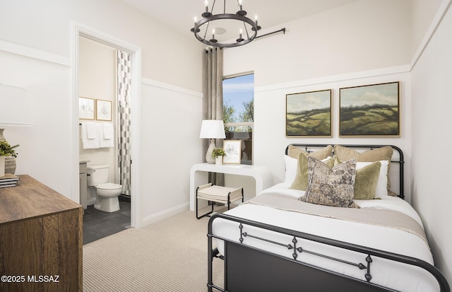 carpeted bedroom with a chandelier, ensuite bathroom, and baseboards