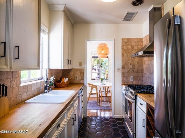 1700 N Winstel Blvd, Tucson, AZ 85716 - kitchen featuring appliances with stainless steel finishes, a sink, wood counters, tasteful backsplash, and wall chimney range hood