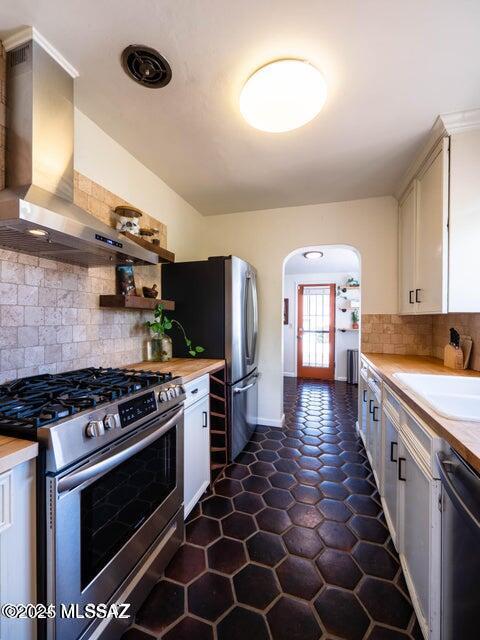 1700 N Winstel Blvd, Tucson, AZ 85716 - kitchen featuring appliances with stainless steel finishes, wall chimney range hood, arched walkways, a sink, and light countertops