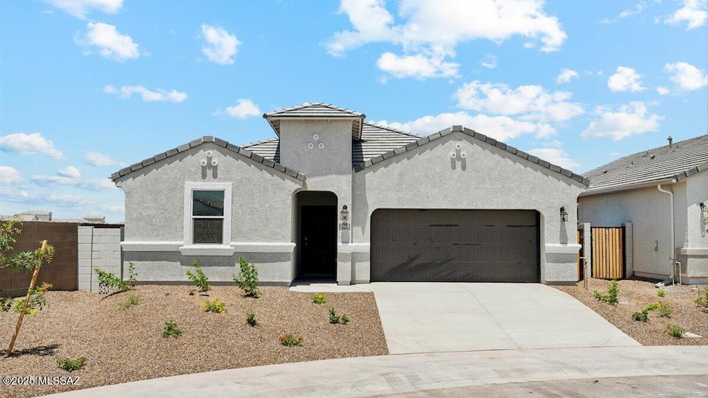 view of front of property with an attached garage, fence, stucco siding, and driveway