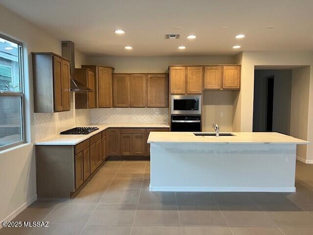 14385 N Saguaro Nest Trl, Marana, AZ 85658 - kitchen featuring stainless steel appliances, wall chimney exhaust hood, a sink, decorative backsplash, and light countertops