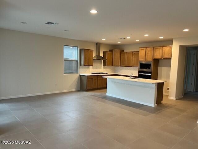 14385 N Saguaro Nest Trl, Marana, AZ 85658 - kitchen with stainless steel microwave, a sink, wall oven, wall chimney range hood, and brown cabinetry
