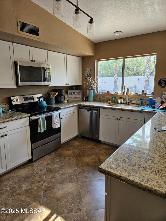 kitchen with stainless steel appliances, a sink, white cabinets, and a textured ceiling