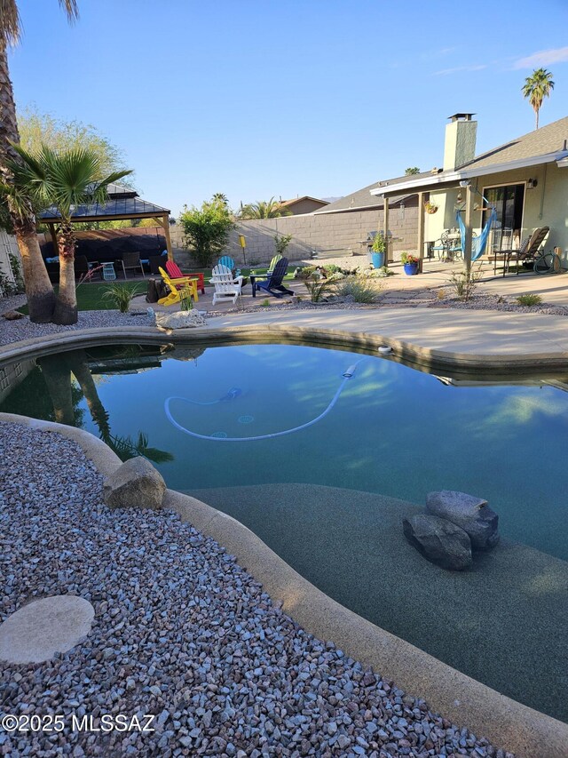 view of swimming pool with a gazebo, fence, and a patio area