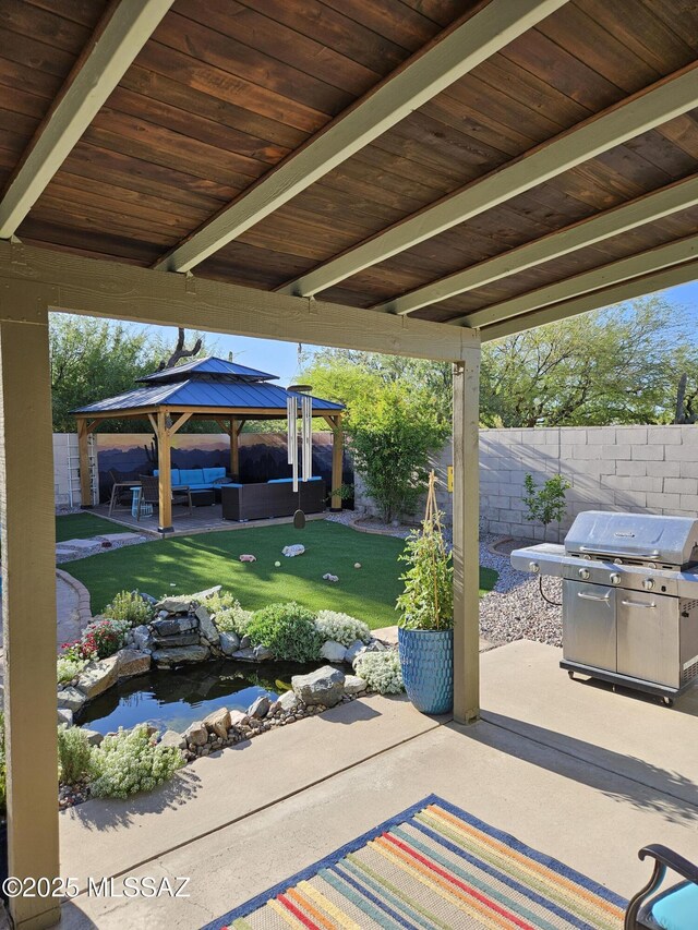 view of patio / terrace with area for grilling, a small pond, a gazebo, a fenced backyard, and outdoor lounge area