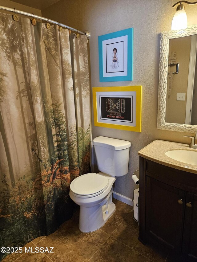 full bath featuring toilet, a textured wall, tile patterned flooring, vanity, and baseboards