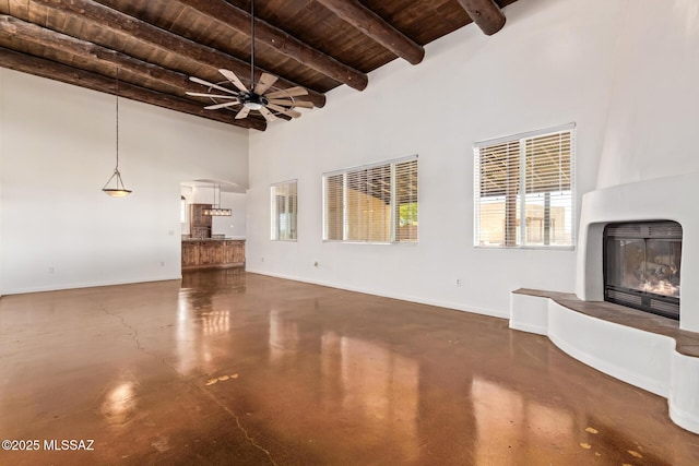 13940 E Hay Bale Trl, Vail, AZ 85641 - unfurnished living room featuring wood ceiling, a fireplace, concrete flooring, a ceiling fan, and beam ceiling