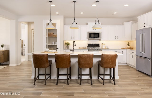 kitchen featuring appliances with stainless steel finishes, a sink, recessed lighting, light wood-style floors, and white cabinetry