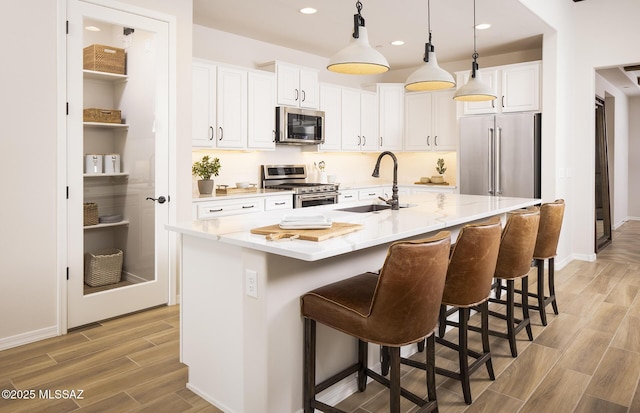 kitchen featuring stainless steel appliances, a sink, light wood-style flooring, white cabinets, and recessed lighting