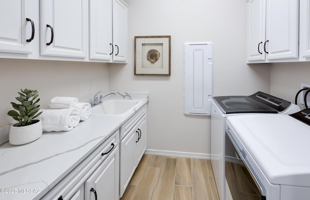 laundry area featuring cabinet space, washing machine and dryer, baseboards, and light wood-style floors
