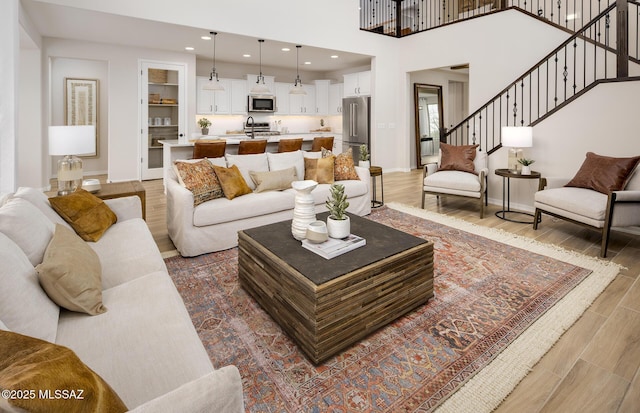 living room with light wood finished floors, baseboards, stairs, and recessed lighting