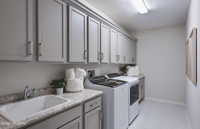 clothes washing area featuring cabinet space, washer and clothes dryer, and baseboards