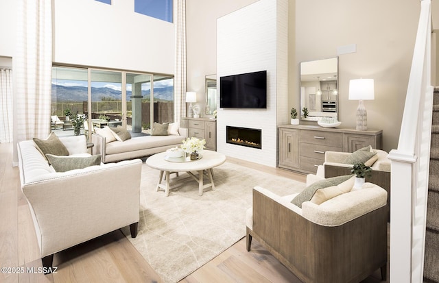 living area with a high ceiling, light wood-style floors, and a fireplace