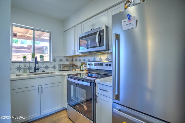 957 N Camino Las Solanas, Tucson, AZ 85710 - kitchen featuring stainless steel appliances, a sink, light countertops, white cabinets, and decorative backsplash