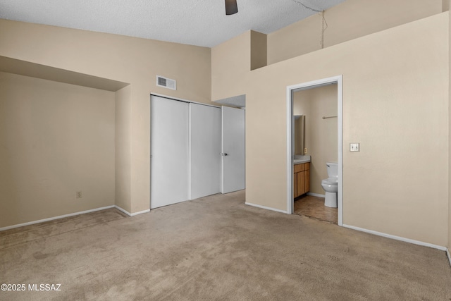 4765 S Windrose Dr, Tucson, AZ 85730 - unfurnished bedroom featuring light carpet, a closet, baseboards, connected bathroom, and high vaulted ceiling