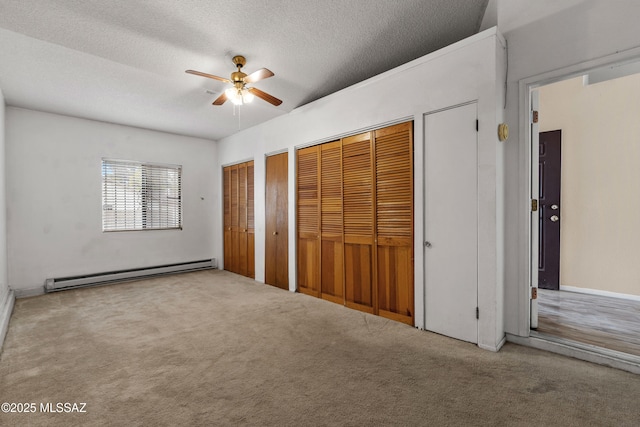4765 S Windrose Dr, Tucson, AZ 85730 - unfurnished bedroom with a baseboard heating unit, multiple closets, carpet floors, a textured ceiling, and ceiling fan