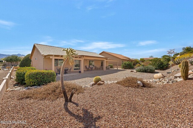 62284 E Iron Crest Dr, Saddlebrooke, AZ 85739 - back of house featuring stucco siding, a patio, a tiled roof, and a mountain view