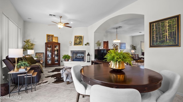 15083 S Placita Rancho Verano, Sahuarita, AZ 85629 - dining area featuring arched walkways, a ceiling fan, a fireplace with raised hearth, and light tile patterned flooring