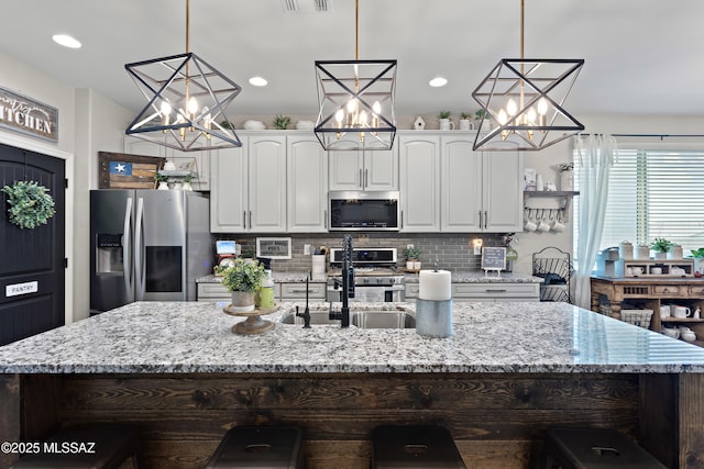 14233 E Hub Dr, Vail, AZ 85641 - kitchen with stainless steel appliances, a sink, a chandelier, an island with sink, and tasteful backsplash
