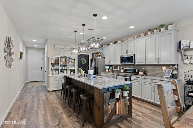 14233 E Hub Dr, Vail, AZ 85641 - kitchen featuring appliances with stainless steel finishes, a chandelier, wood finished floors, a kitchen breakfast bar, and recessed lighting