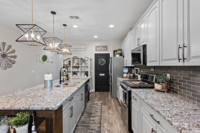 14233 E Hub Dr, Vail, AZ 85641 - kitchen featuring stainless steel appliances, a sink, an island with sink, wood finished floors, and tasteful backsplash