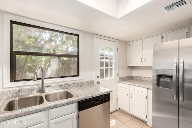 kitchen with stainless steel appliances, a sink, light tile patterned floors, and white cabinets