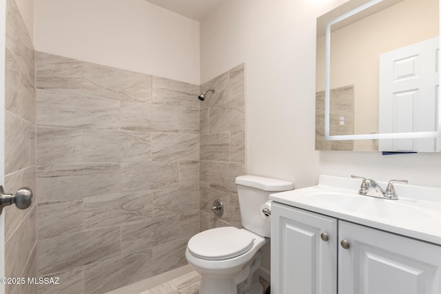 full bath with tiled shower, vanity, and toilet