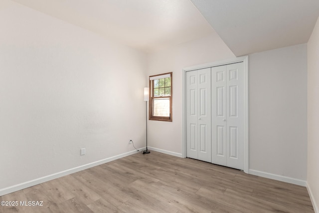 unfurnished bedroom with light wood finished floors, baseboards, and a closet