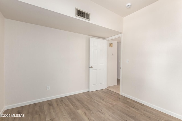 spare room with wood finished floors, baseboards, and a smoke detector