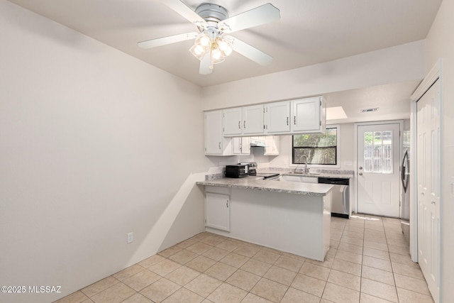 kitchen with appliances with stainless steel finishes, a peninsula, a sink, light countertops, and light tile patterned floors